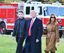 Donald Trump with his wife and son walking across grass with a fire truck in the background