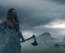 Viking warrior holding an ax and a shied on a foggy landscape