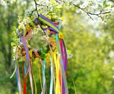Spring flower wreath with colorful ribbons on tree in garden, green natural background. floral decor. Symbol of Beltane, Wiccan Celtic Holiday beginning of summer. pagan witch traditions, rituals flower wreath with colorful ribbons on tree in garden, green natural background. floral decor. Symbol of Beltane, Wiccan Celtic Holiday beginning of summer. pagan witch traditions, rituals