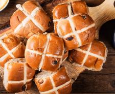 Hot cross buns on a wooden chopping board