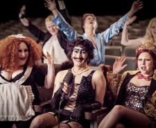 Documentary contributors sitting in theatre seating dressed up as members of the Rocky Horror cast