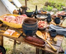 Chopped raw meat, homemade food and pottery on the table at historical reenactment of Vikings lifestyle around 11th century