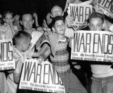 Young people in the US celebrate VJ Day while holding newspapers with the headline 'WAR ENDS'